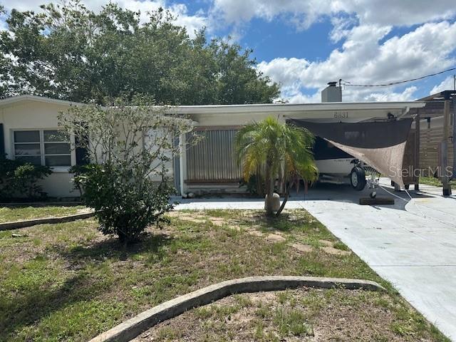 view of front facade featuring an attached carport, concrete driveway, and a front lawn