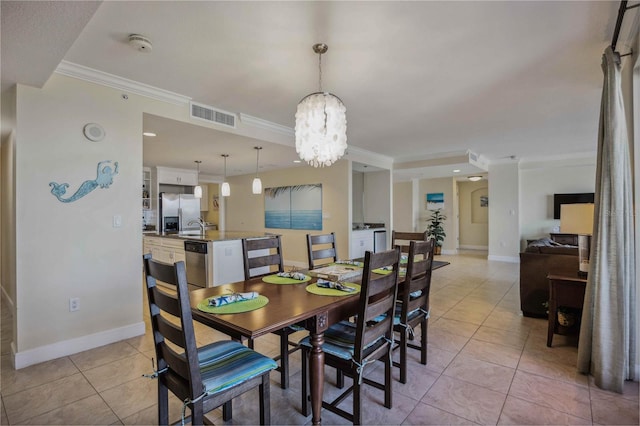 dining room featuring light tile patterned floors, sink, a chandelier, and ornamental molding