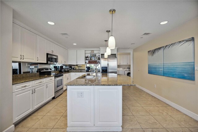 kitchen with dark stone counters, white cabinetry, sink, appliances with stainless steel finishes, and light tile patterned floors