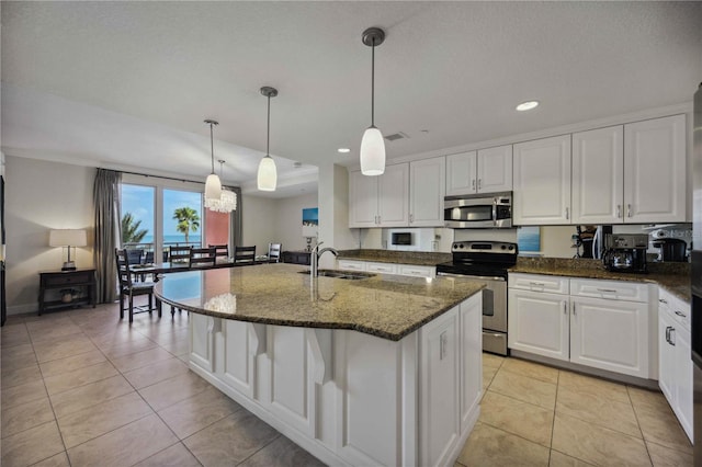 kitchen featuring appliances with stainless steel finishes, dark stone counters, sink, decorative light fixtures, and white cabinetry