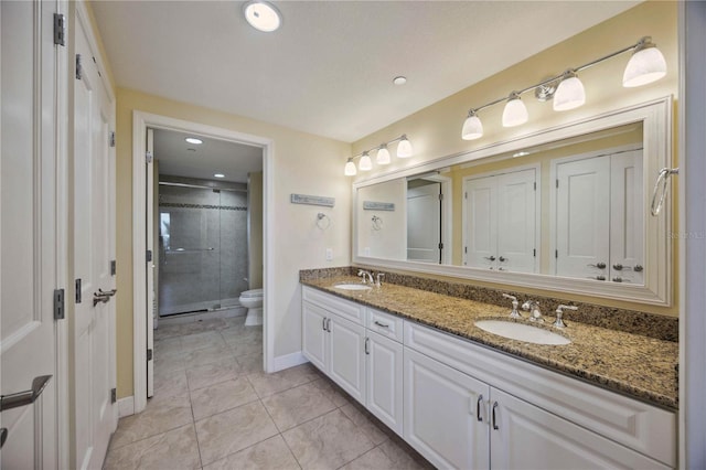 bathroom featuring tile patterned floors, vanity, toilet, and a shower with shower door