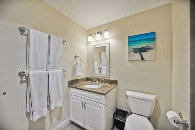 bathroom with toilet, vanity, and a textured ceiling