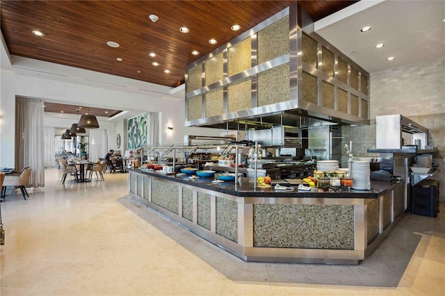 kitchen featuring a towering ceiling, wall chimney range hood, a tray ceiling, and wooden ceiling