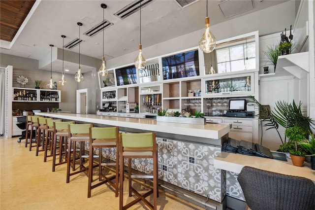 bar with white cabinetry, decorative light fixtures, and a towering ceiling