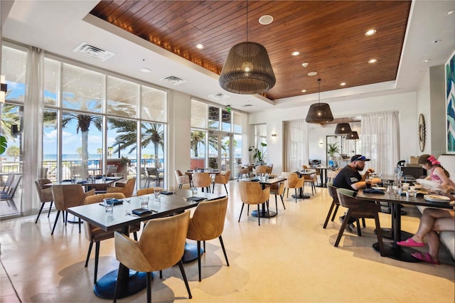 dining space featuring a wall of windows, wooden ceiling, a high ceiling, and a tray ceiling