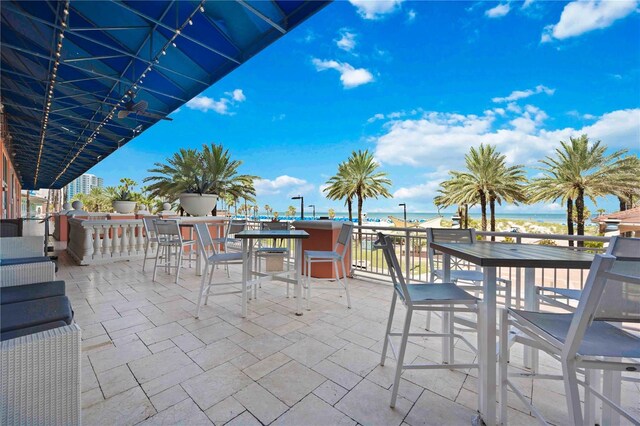 view of patio with a bar, a water view, and a view of the beach