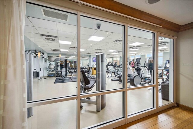 workout area featuring a drop ceiling and light wood-type flooring