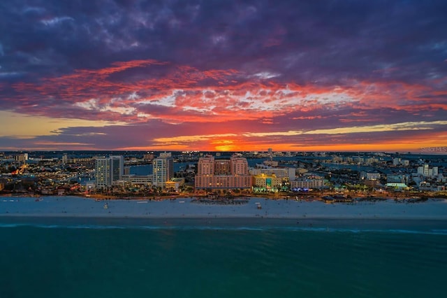 aerial view at dusk with a water view and a beach view