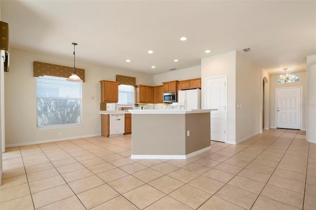 kitchen featuring light tile patterned flooring, a center island, hanging light fixtures, and white appliances