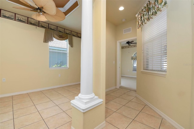 interior space with decorative columns, ceiling fan, and light tile patterned floors