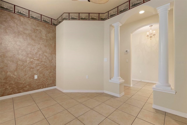 spare room with ornate columns, light tile patterned floors, and a chandelier