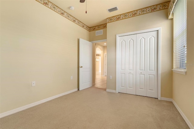 unfurnished bedroom with light carpet, a closet, and ceiling fan