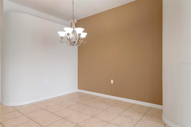 spare room with a chandelier and light tile patterned floors