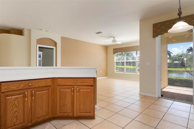 kitchen with pendant lighting, a water view, light tile patterned floors, and ceiling fan