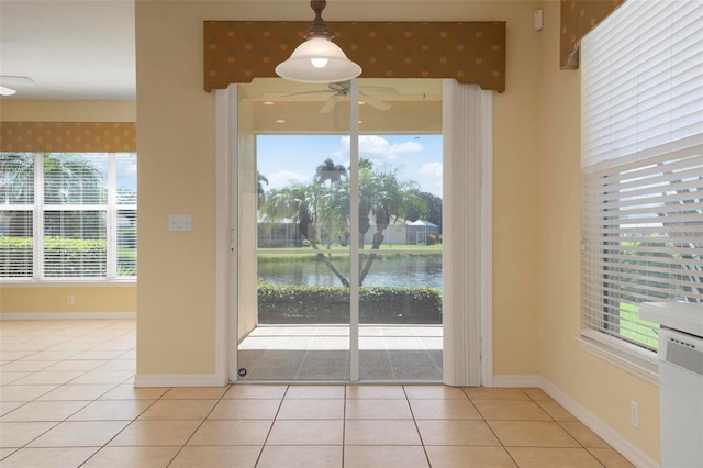 interior space featuring a water view, ceiling fan, a wealth of natural light, and light tile patterned floors