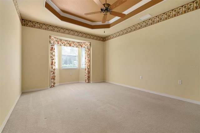 empty room with ceiling fan, crown molding, carpet floors, and a tray ceiling