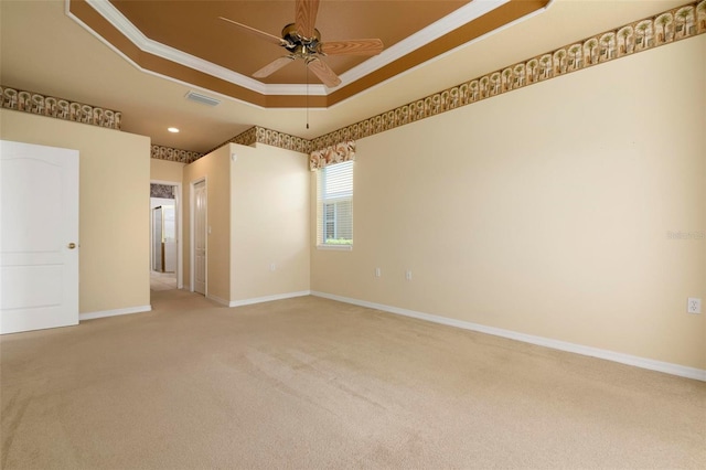 carpeted empty room with ceiling fan, a raised ceiling, and crown molding