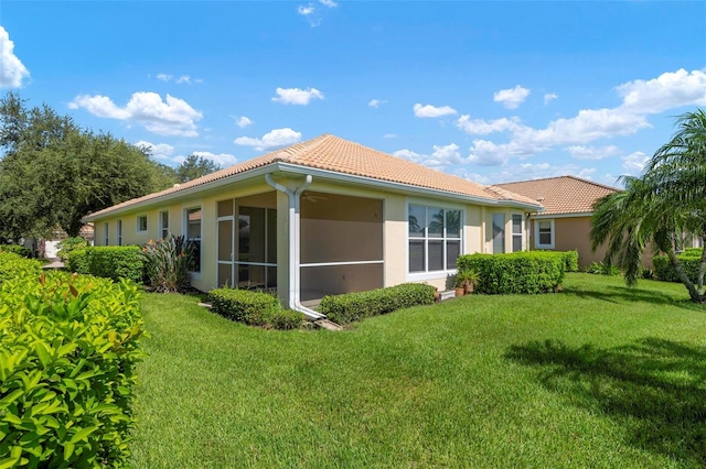 rear view of property featuring a sunroom and a yard