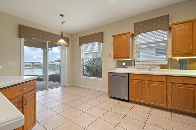 kitchen featuring sink, a water view, hanging light fixtures, light tile patterned floors, and dishwasher