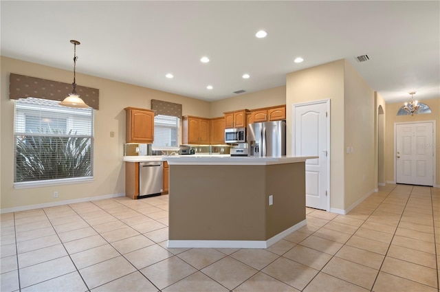 kitchen featuring decorative light fixtures, light tile patterned flooring, stainless steel appliances, and a kitchen island