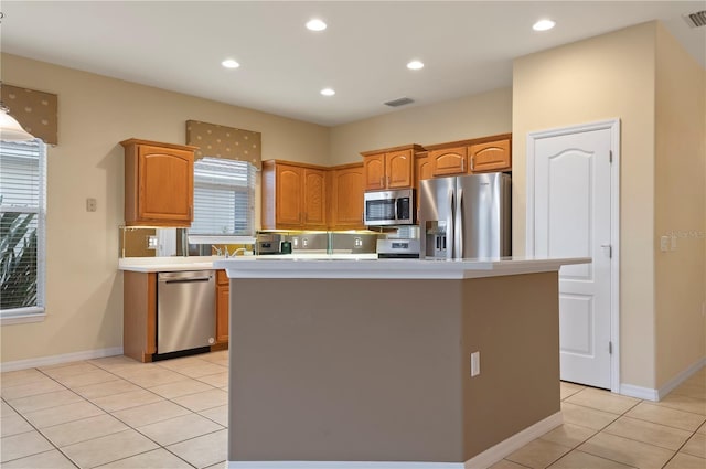 kitchen featuring stainless steel appliances, light tile patterned flooring, a center island, and tasteful backsplash