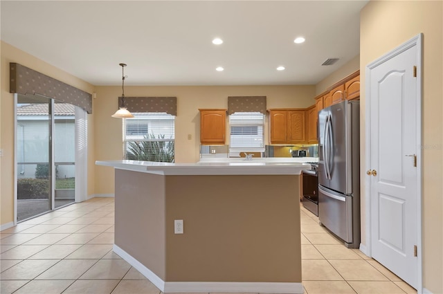 kitchen featuring pendant lighting, appliances with stainless steel finishes, a center island with sink, and light tile patterned floors