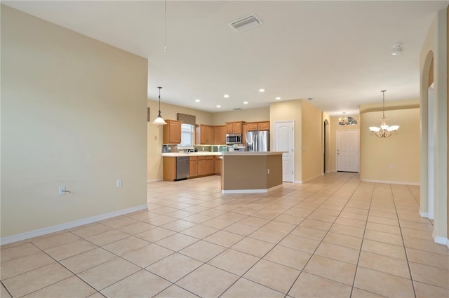 kitchen with stainless steel appliances, light tile patterned flooring, hanging light fixtures, and a center island