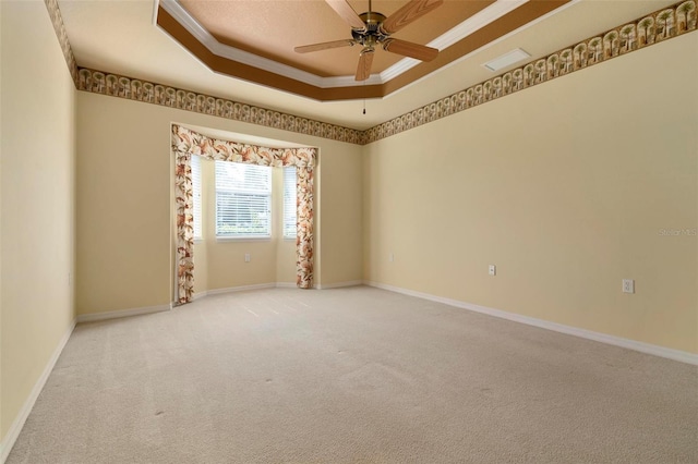 empty room featuring ceiling fan, light colored carpet, ornamental molding, and a tray ceiling