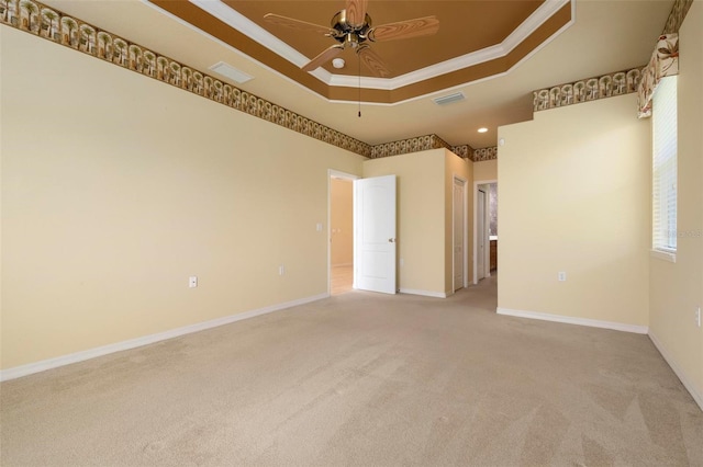 carpeted spare room with ceiling fan, ornamental molding, and a tray ceiling