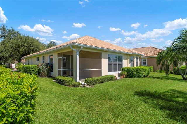 back of property with a sunroom and a lawn