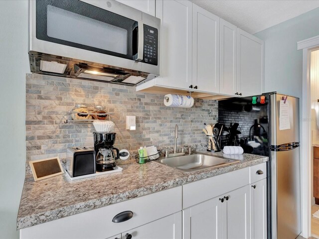 kitchen featuring sink, white cabinetry, decorative backsplash, and stainless steel appliances