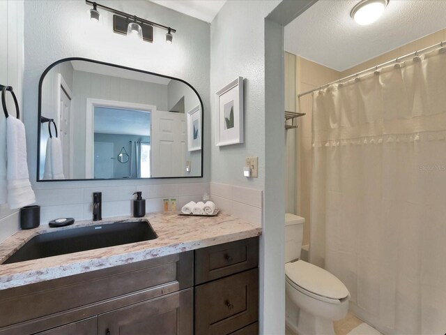 bathroom with vanity, toilet, a textured ceiling, and tasteful backsplash