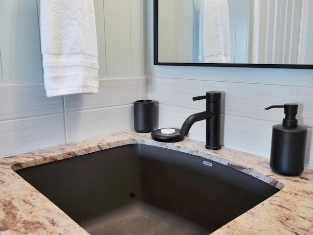 room details featuring sink, white cabinets, tasteful backsplash, and light stone countertops