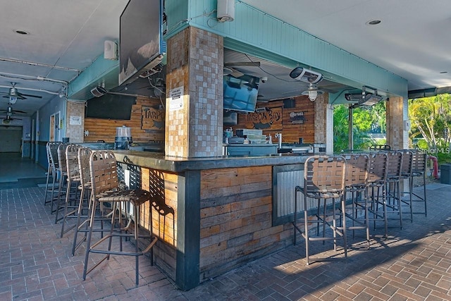 bar with ceiling fan and wooden walls