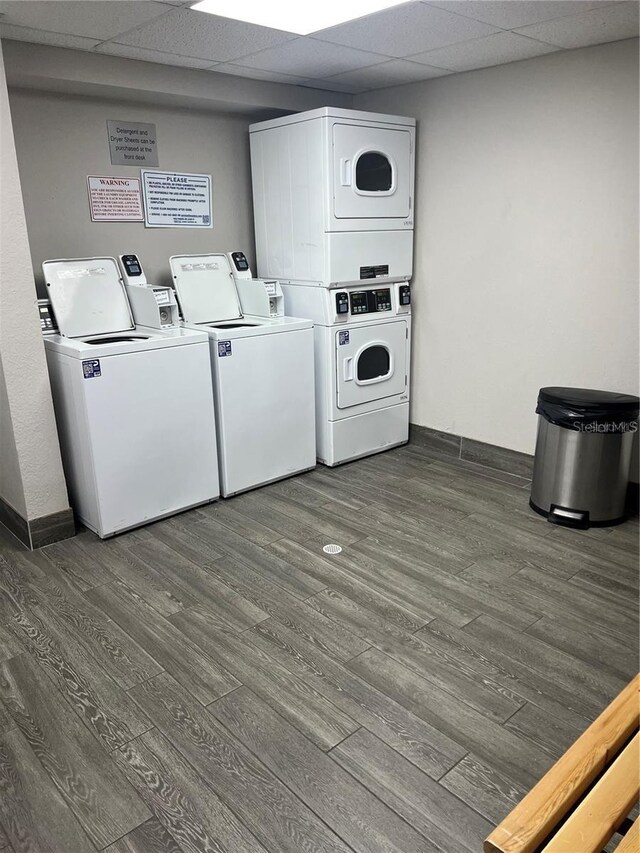 clothes washing area with stacked washer and clothes dryer and dark hardwood / wood-style floors