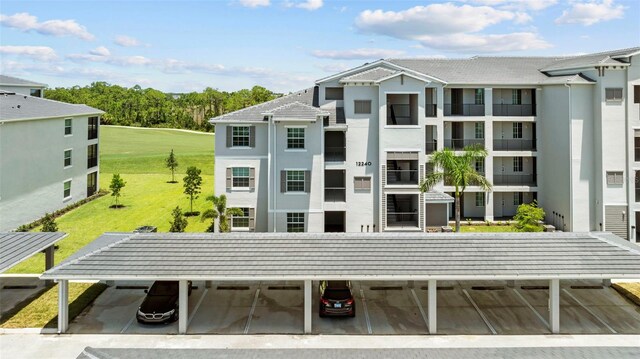 exterior space with a lawn, a balcony, and a carport