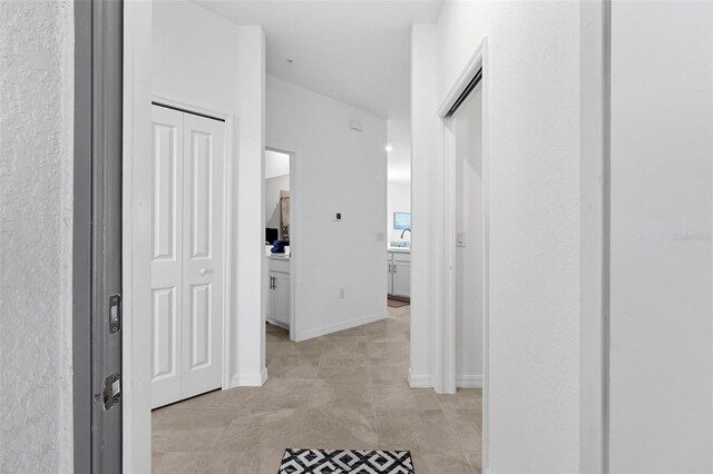 corridor featuring sink and light tile patterned floors