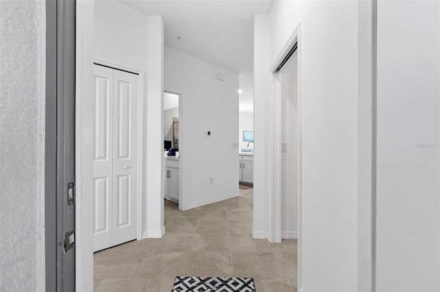 corridor featuring baseboards and a sink