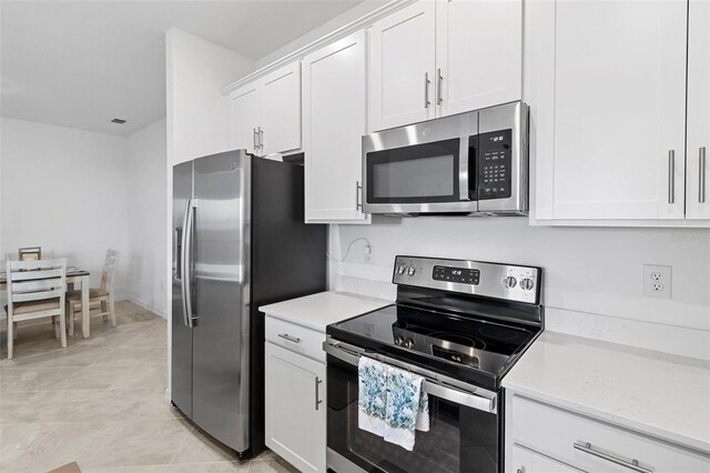 kitchen with white cabinetry, light tile patterned floors, and stainless steel appliances