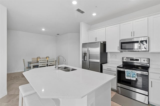 kitchen featuring a center island with sink, stainless steel appliances, recessed lighting, white cabinetry, and a sink