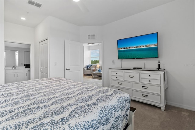 carpeted bedroom with a closet, ensuite bath, and ceiling fan