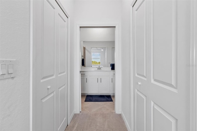 hallway featuring light carpet and a sink