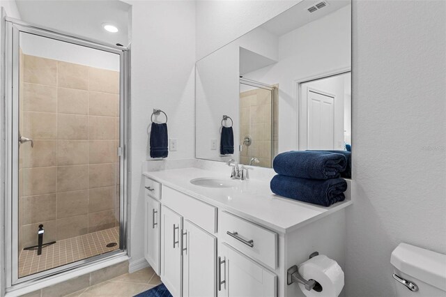 bathroom featuring walk in shower, vanity, toilet, and tile patterned floors