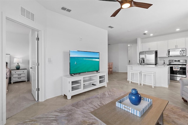 tiled living room featuring ceiling fan and sink