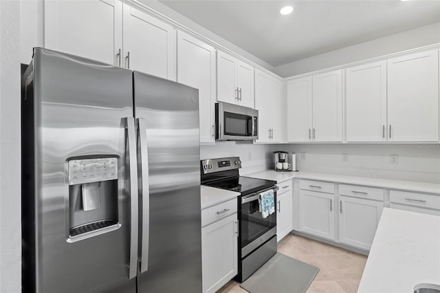 kitchen featuring light tile patterned floors, light countertops, appliances with stainless steel finishes, and white cabinets