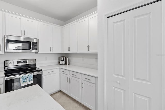 kitchen with light stone countertops, light tile patterned flooring, stainless steel appliances, and white cabinetry