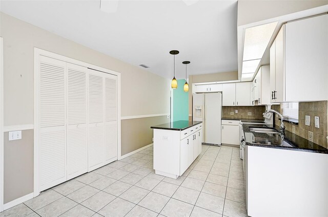 kitchen with pendant lighting, white fridge with ice dispenser, white cabinetry, and a kitchen island