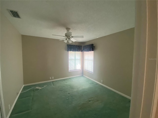 carpeted empty room featuring baseboards, visible vents, and a ceiling fan