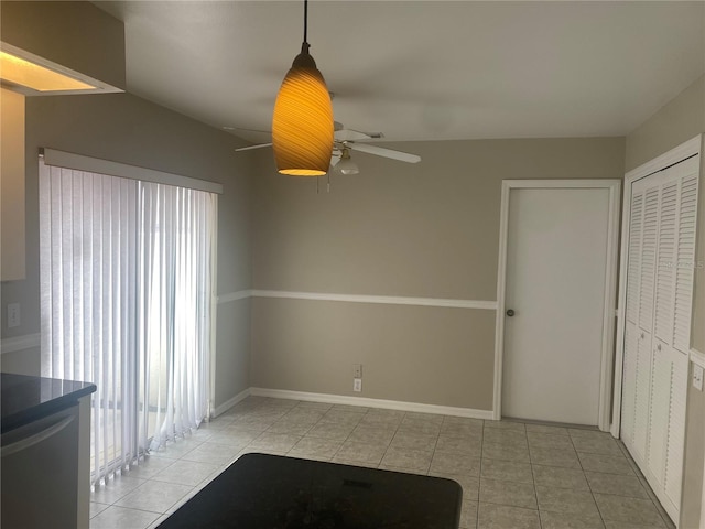 interior space with vaulted ceiling, tile patterned flooring, a ceiling fan, and baseboards