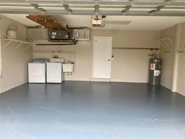 garage with concrete block wall, water heater, a sink, and independent washer and dryer